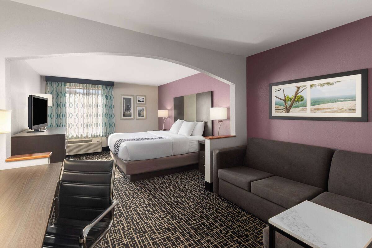 A hotel room with a bed, a sofa, a desk, and a TV.