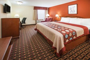 Una habitación de hotel con una cama grande, un escritorio, una silla y un televisor en la pared.