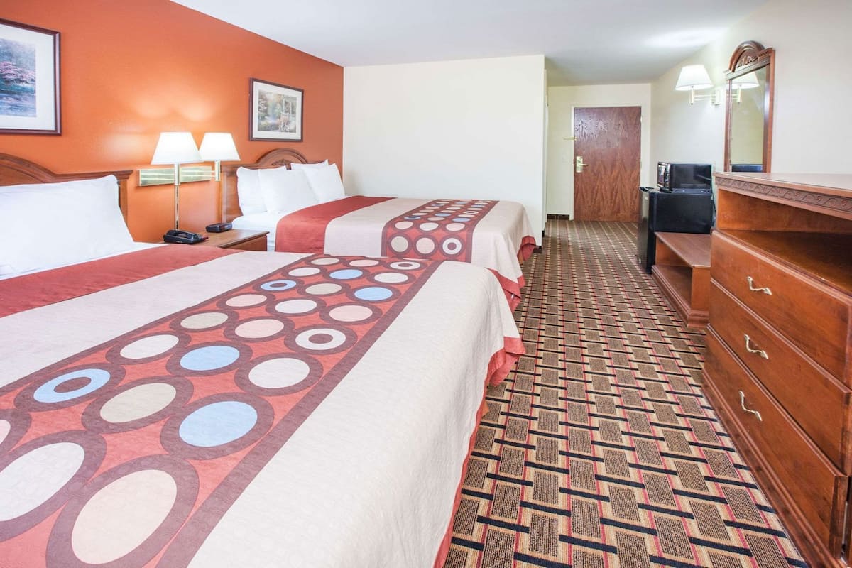 Een hotelkamer met twee bedden, een dressoir, een bureau en een spiegel.