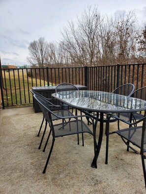 An outdoor patio with a glass-top table and black metal chairs. - Super 8 by Wyndham Troy (Troy)