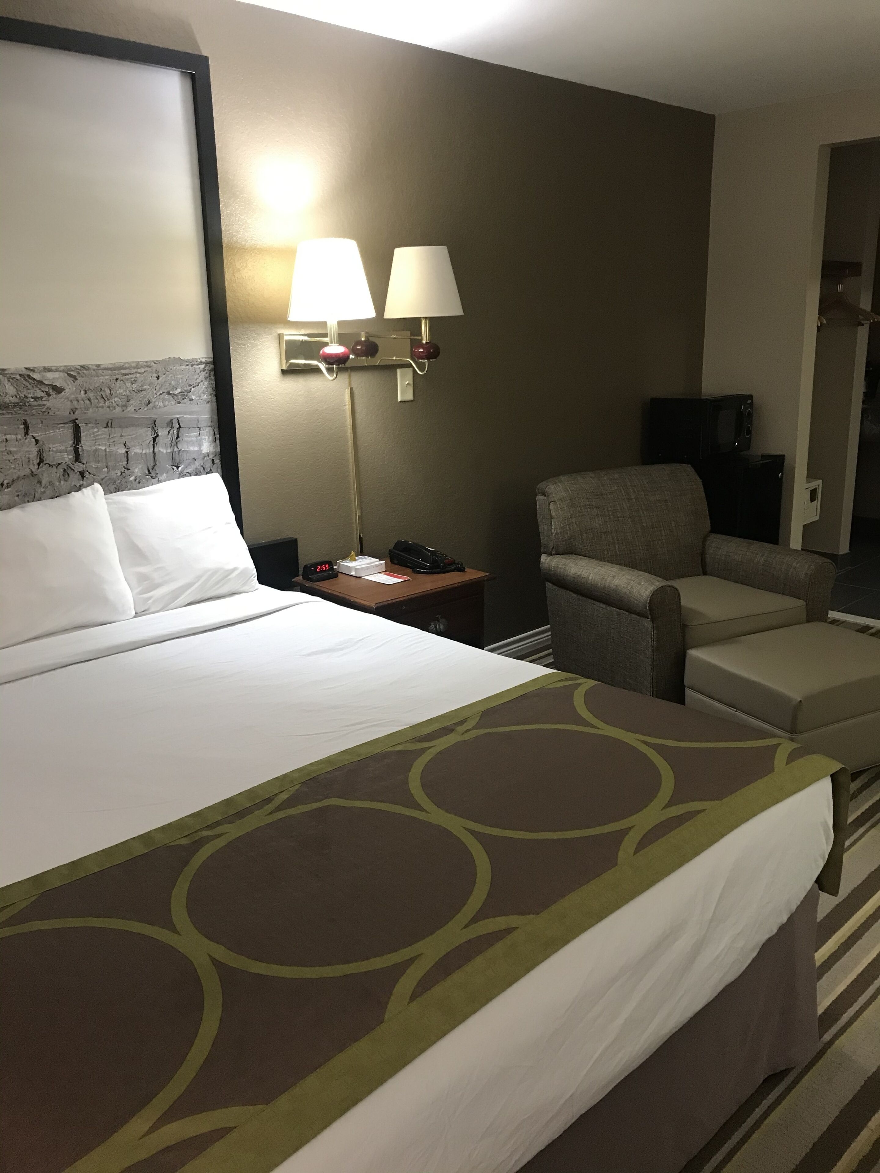 A hotel room with a large bed, two bedside lamps, a chair, and a television.