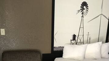 Een hotelkamer met een bed, een stoel en een groot raam met uitzicht op windturbines.