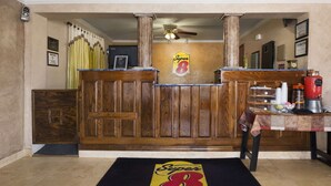 Un coin bar avec un comptoir en bois, le logo de Super 8 sur le mur et une machine à café rouge.