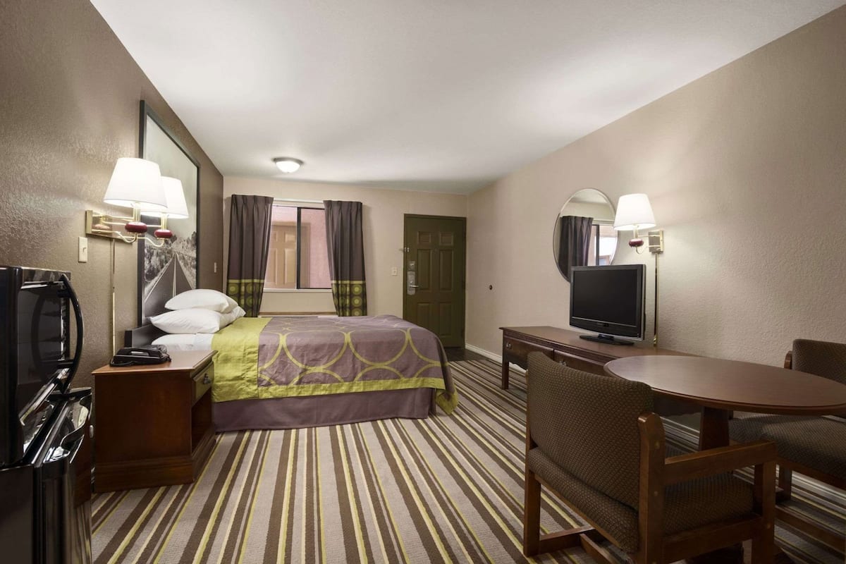 Ein Hotelzimmer mit einem Bett, einem Fernseher, einem Schreibtisch und einem Sessel.