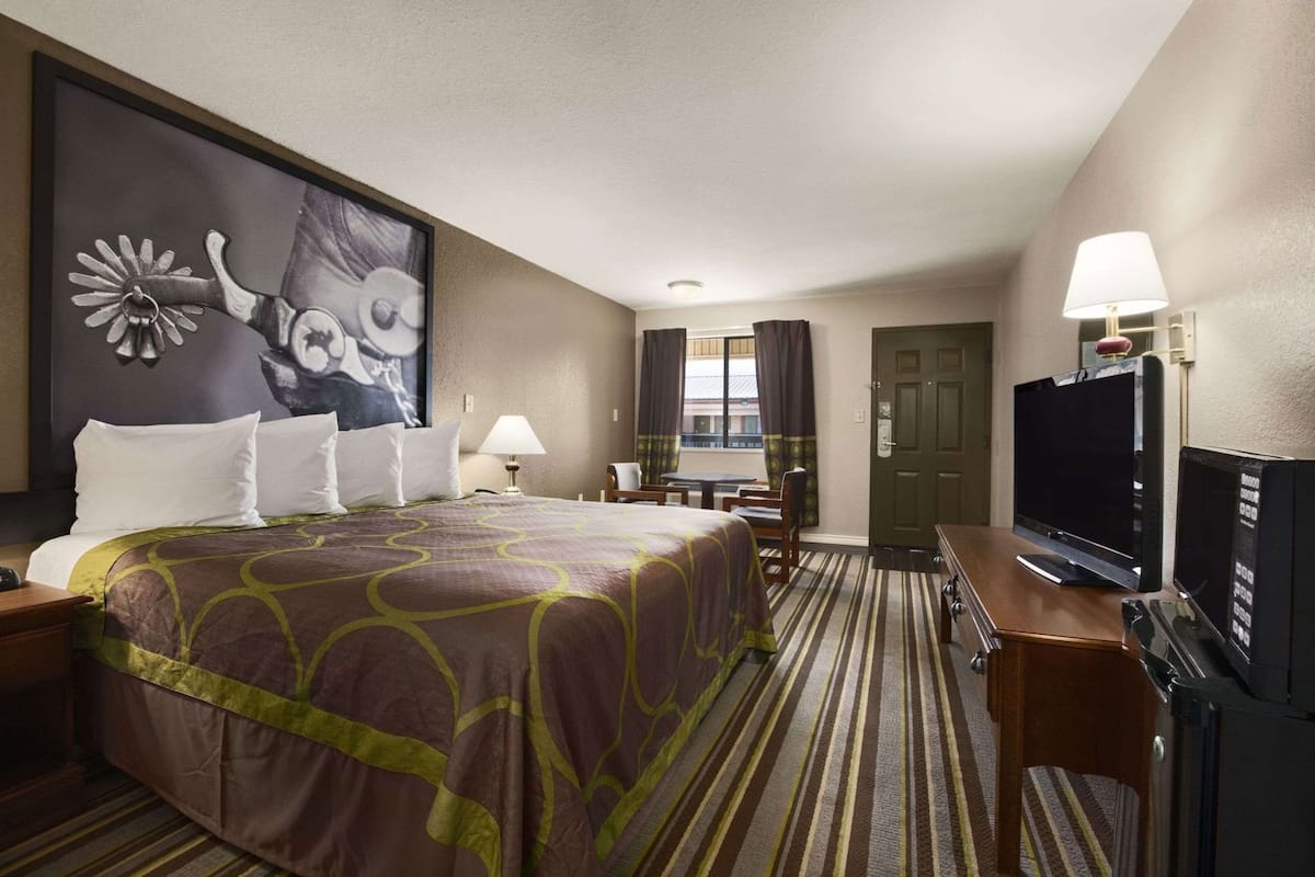 Ein Hotelzimmer mit einem großen Bett, einem Fernseher, einem Schreibtisch und einem Sessel.