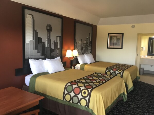 A hotel room with two beds, a desk, a chair, a lamp, a framed picture, and a cityscape mural on the wall. - Super 8 by Wyndham Fairfield Tx (Fairfield)