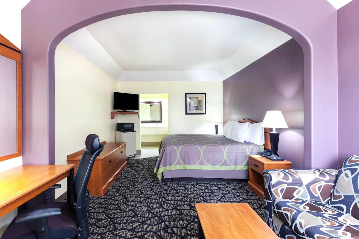 Een hotelkamer met een bed, bureau, stoel, bank en een televisie.