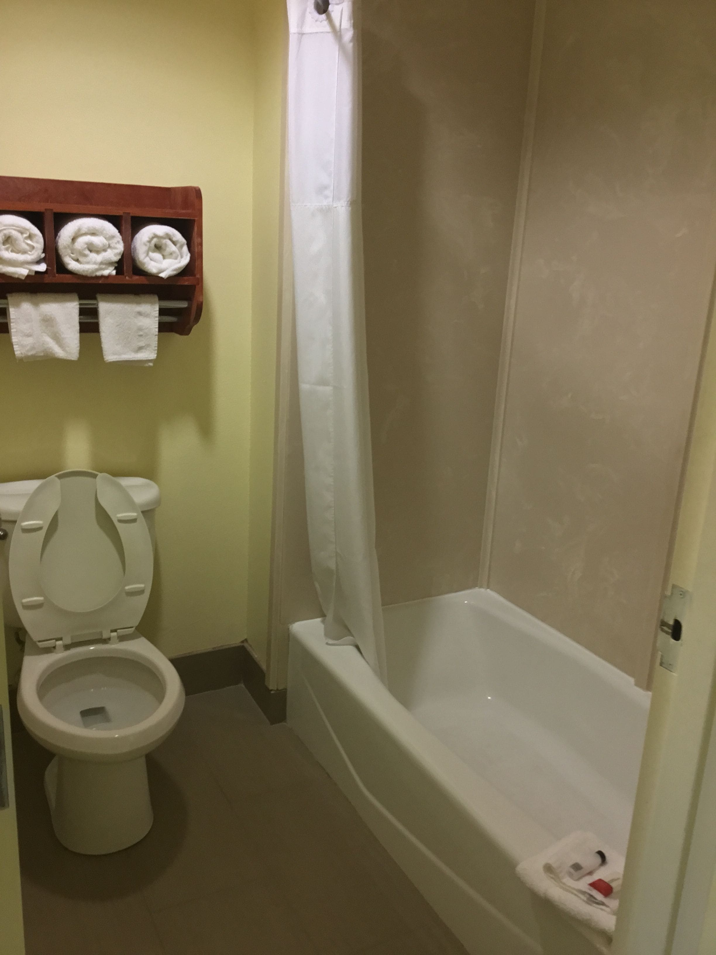 Ein Badezimmer mit Toilette, einer Duschkabine und einem Handtuchhalter mit Handtüchern.