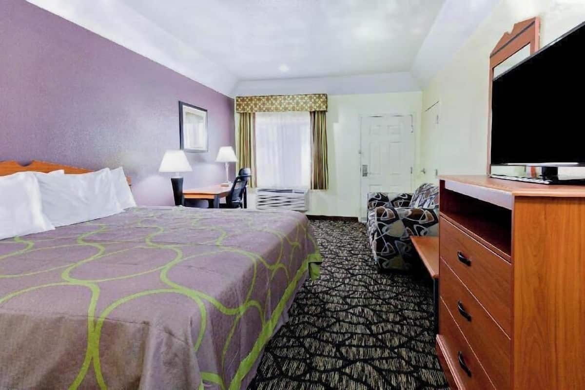 Een hotelkamer met een bed, een bureau, een stoel, een televisie en een kledingkast.