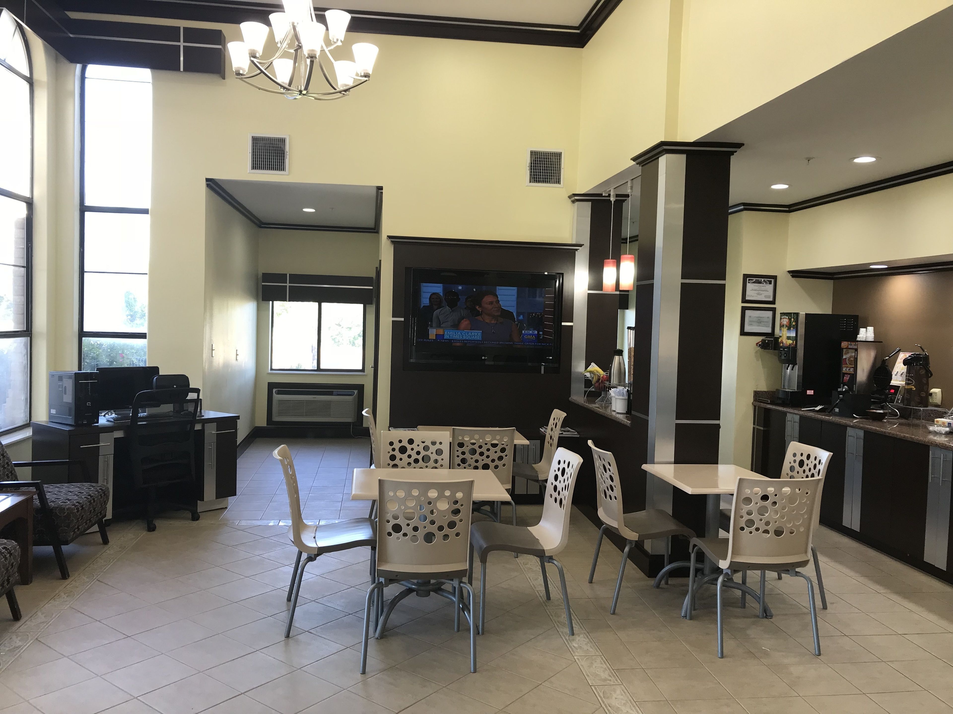 A modern dining area with a TV, seating, and a coffee station.