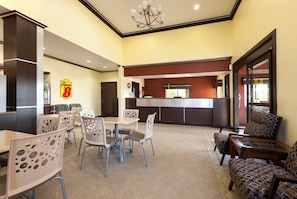 A hotel lobby with a reception desk, seating area, and a clock on the wall.