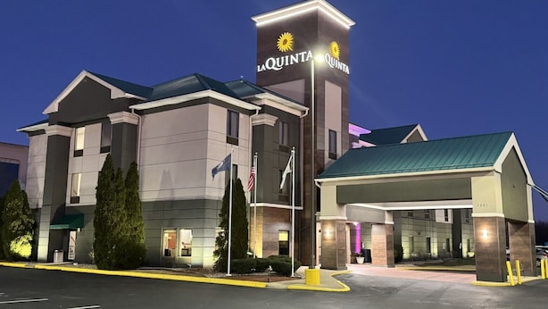 A La Quinta hotel with a modern design, featuring a prominent entrance, a gas station, and a well-lit facade.