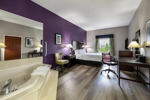 Habitación de hotel con cama, escritorio, silla y bañera.