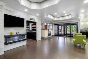 Un vestíbulo amplio con televisión de pantalla plana, mostrador de recepción y una chimenea decorativa.