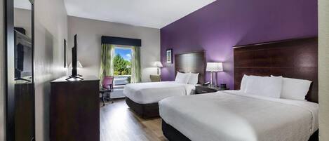 Une chambre d’hôtel avec deux lits, un bureau, une chaise, un miroir et une fenêtre avec des rideaux.