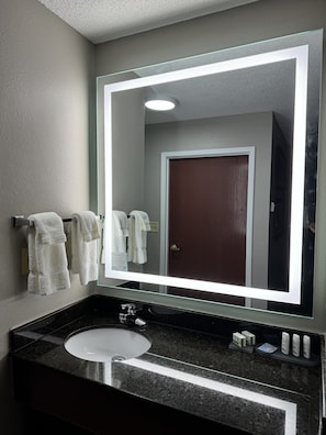 A bathroom with a large mirror, a sink, and a towel rack. - La Quinta Inn & Suites by Wyndham Louisville East (Louisville)
