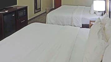 A hotel room with two beds, a TV, and a desk.