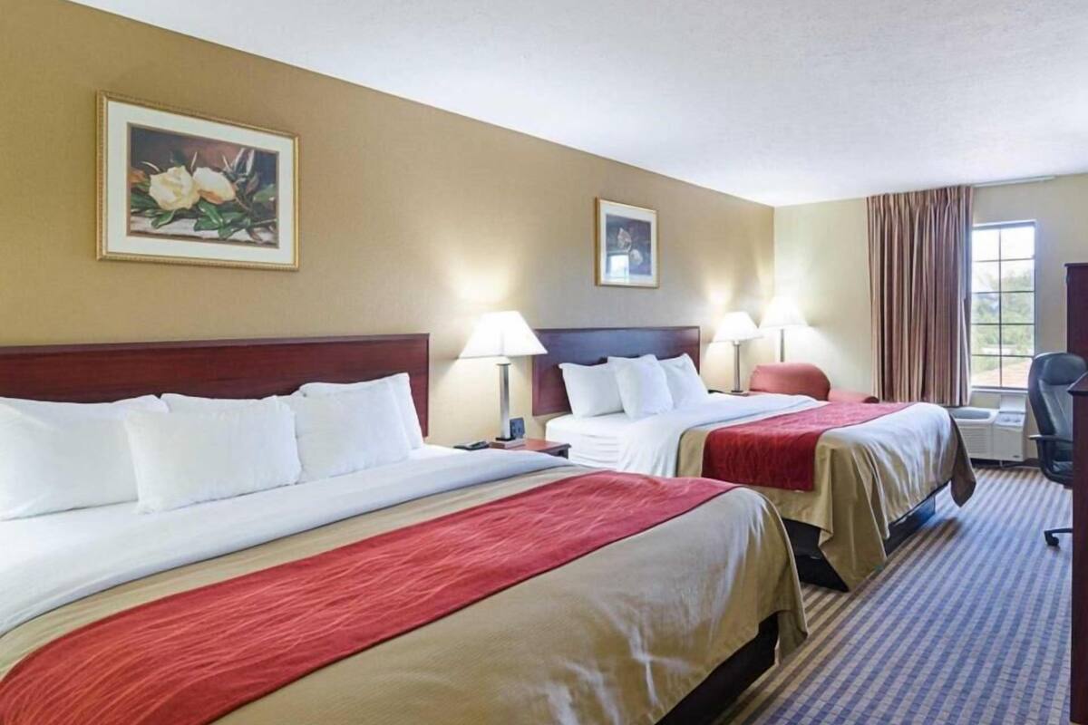 A hotel room with two beds, a desk, and a chair.