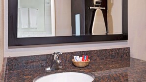 A bathroom with a granite countertop, a sink, a mirror, and a basket containing toiletries. - Super 8 by Wyndham Los Angeles-Culver City Area (Los Angeles)