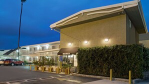 A hotel with a flat roof, a well-lit entrance, and a parking lot with cars. - Super 8 by Wyndham Los Angeles-Culver City Area (Los Angeles)