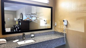 A bathroom with a large mirror, a sink, a towel, and a hairdryer on the wall. - Super 8 by Wyndham Lafayette / Purdue Area (Lafayette)