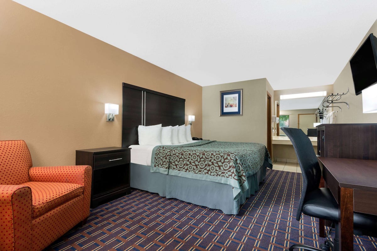 A hotel room with a bed, a desk, a chair, and a sofa.