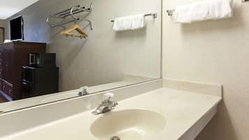 A bathroom with a large mirror, a sink, and towel racks.