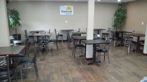 A dining area with multiple tables and chairs, a sign for 'Daybreak Breakfast', and potted plants. - Days Inn by Wyndham Maumee/Toledo (Maumee)