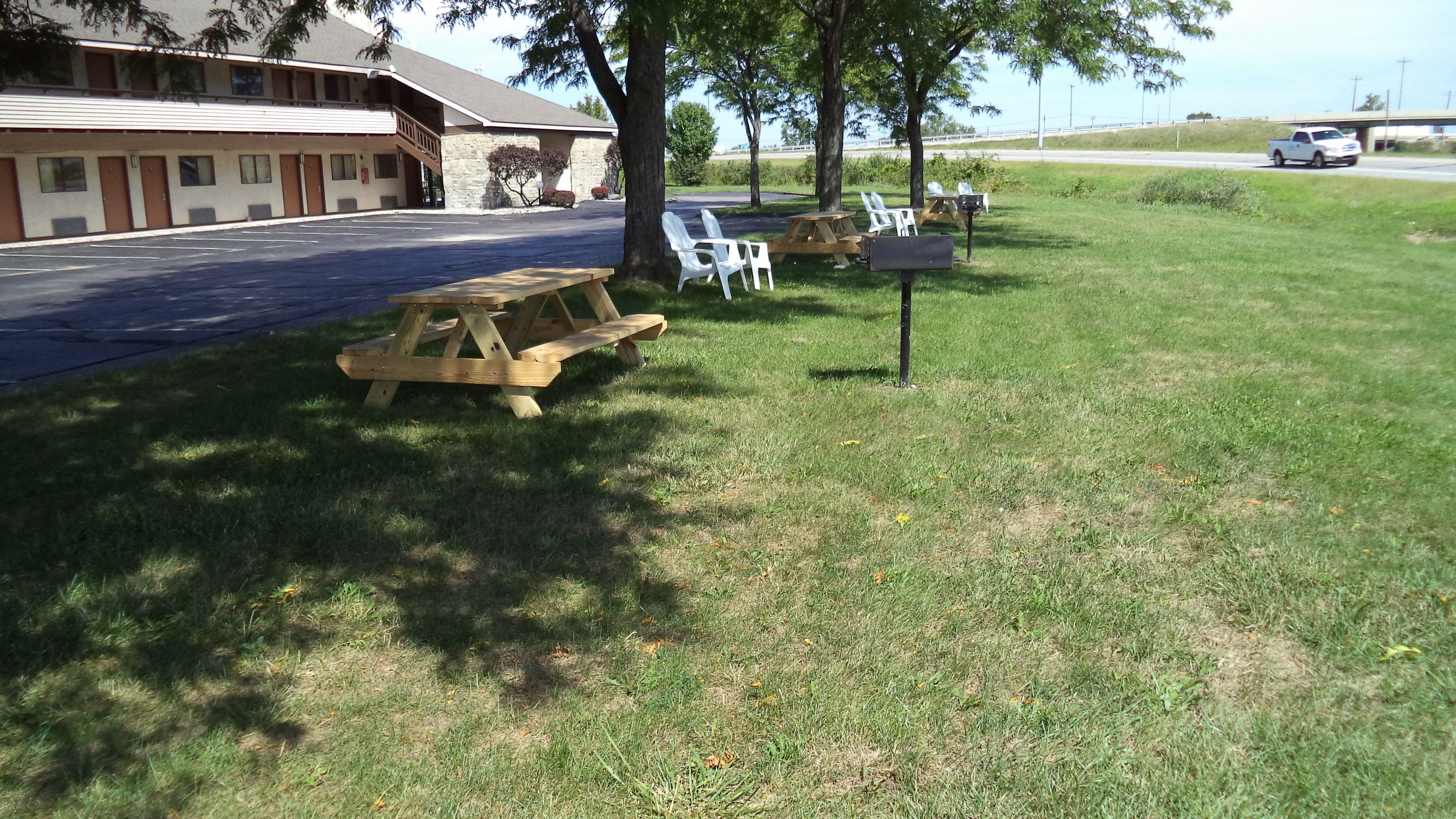 A motel with a parking lot, picnic tables, and outdoor seating.