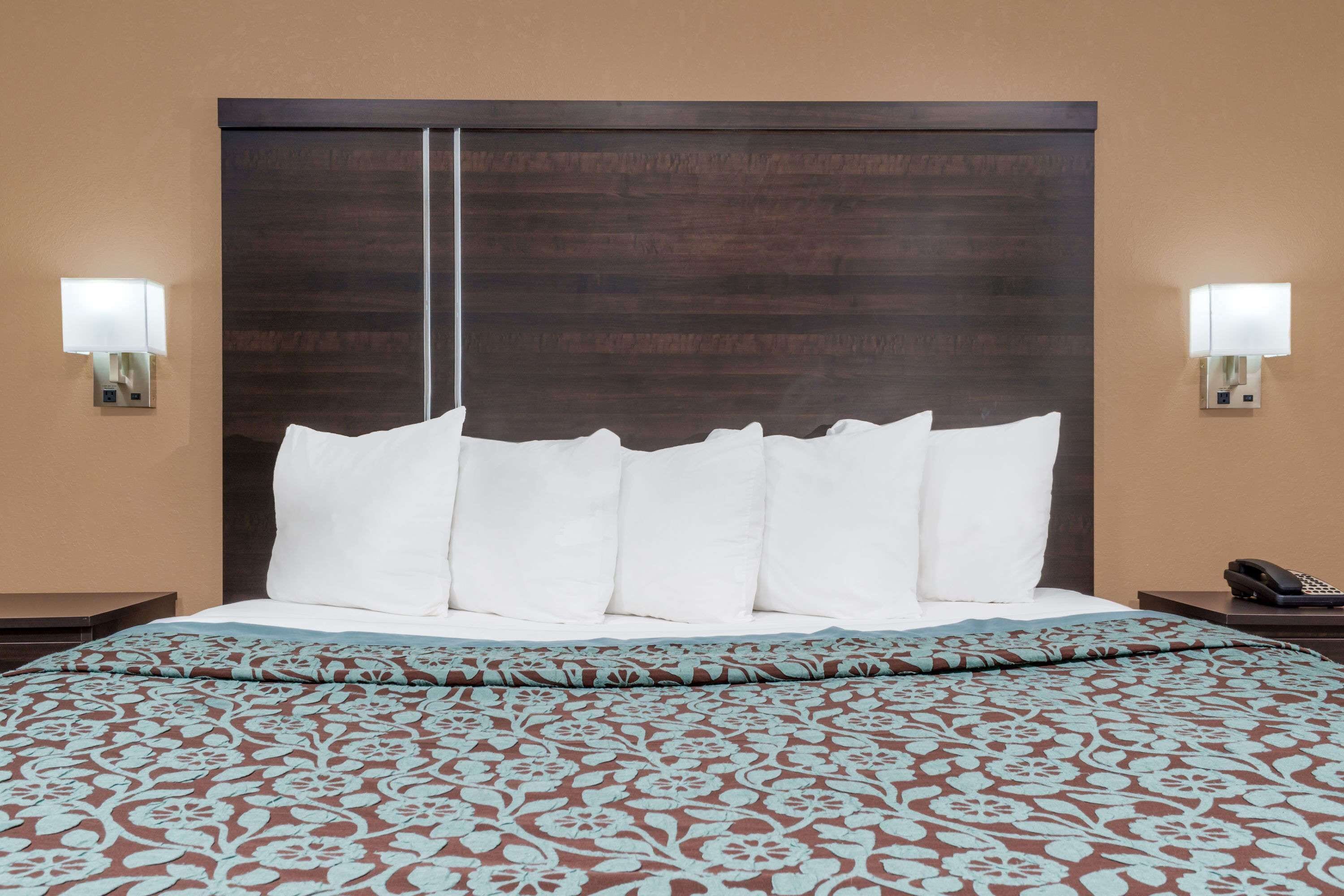 Una habitación de hotel con una cama grande, dos lámparas de noche y un teléfono en la mesita.