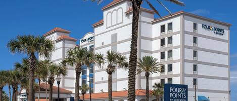 A multi-story hotel with a white facade and red roof, featuring a prominent 'Four Points by Sheraton' sign.
