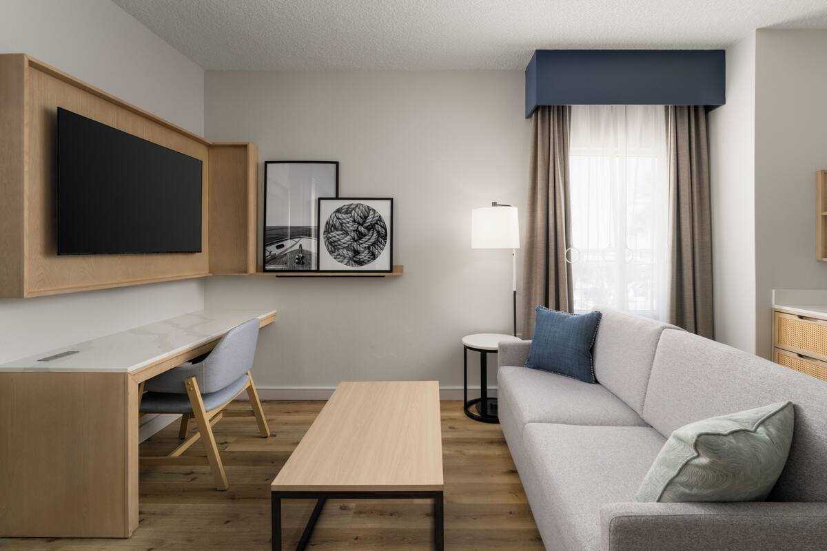Una sala de estar moderna con una televisión de pantalla plana, un escritorio, un sofá y una lámpara.