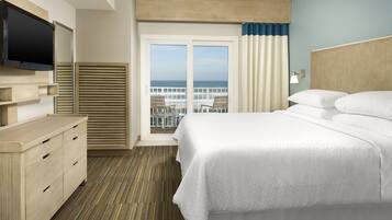 Una habitación de hotel con cama, televisión, escritorio y vista al océano.