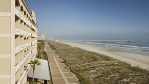 Een kusthotel met een lange boulevard, toegang tot het strand en een pier in de verte.