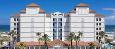 A large, white hotel with a central entrance and a sign reading "Four Points by Sheraton."