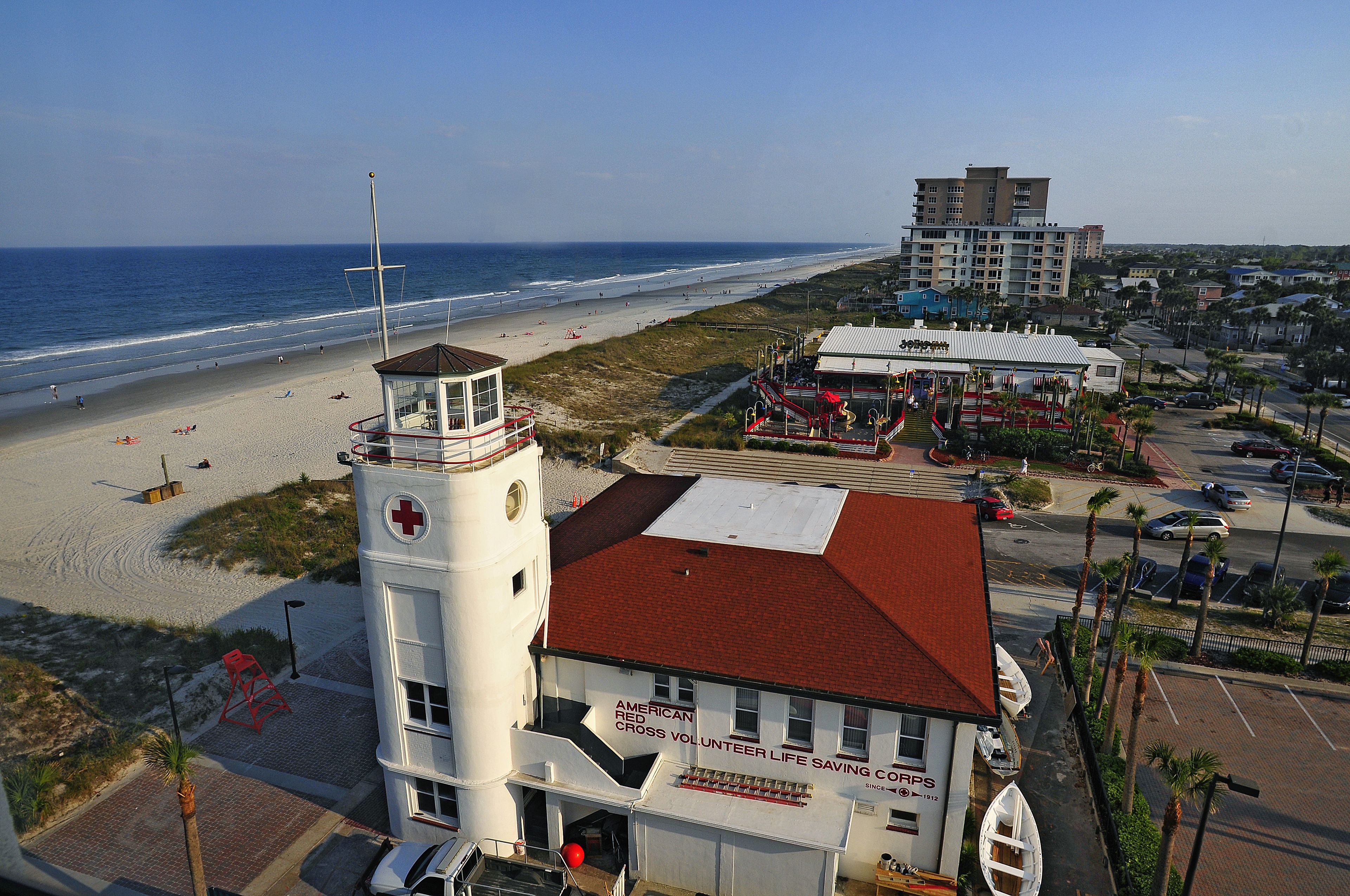 A lifeguard tower and a building with a red roof, adjacent to a beach.