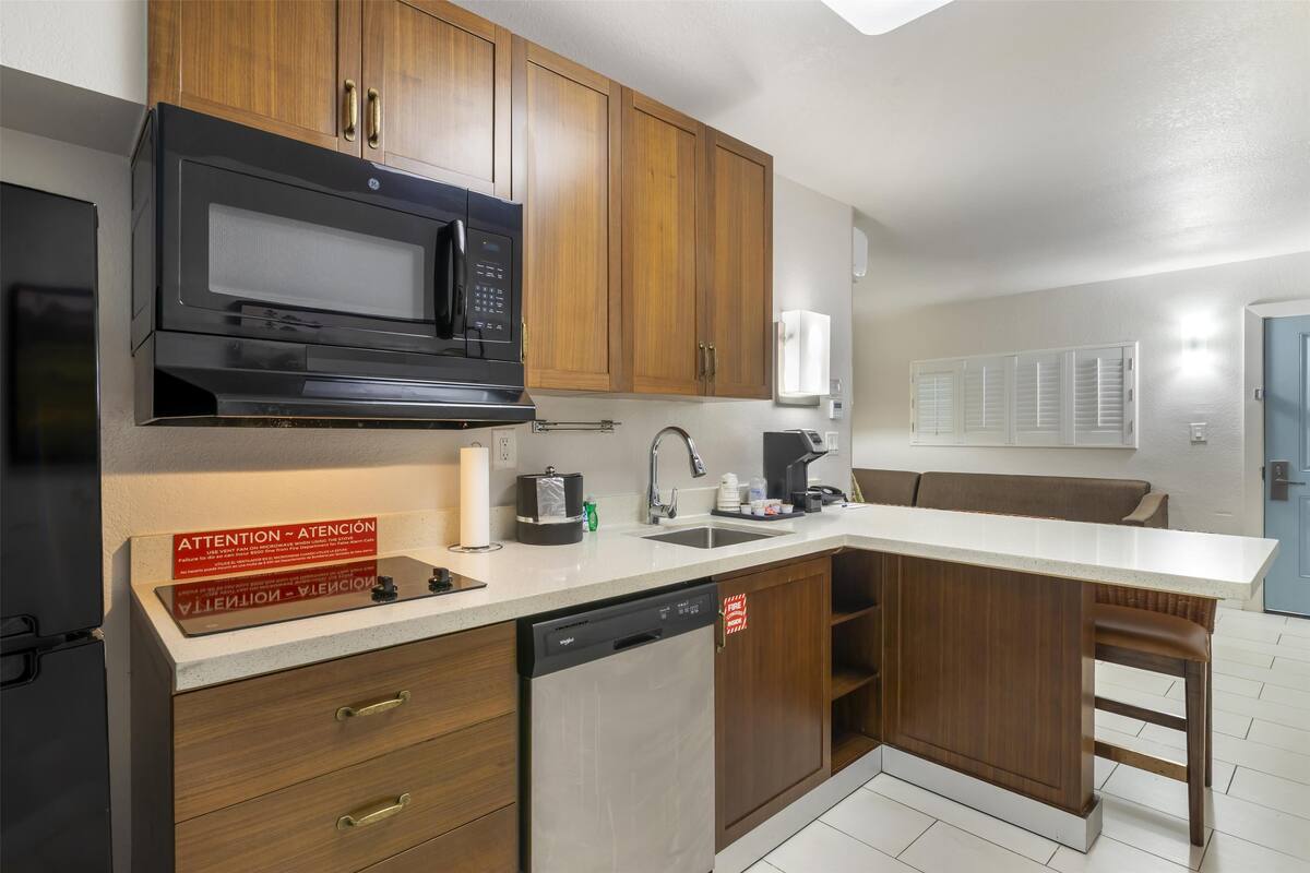 A modern kitchen with wooden cabinets, a microwave, a dishwasher, and a countertop with a sink.