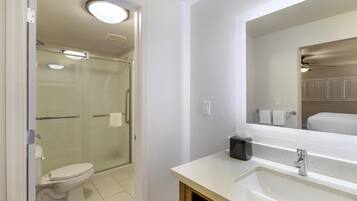 A modern bathroom with a glass-enclosed shower, a white toilet, and a sink with a mirror.