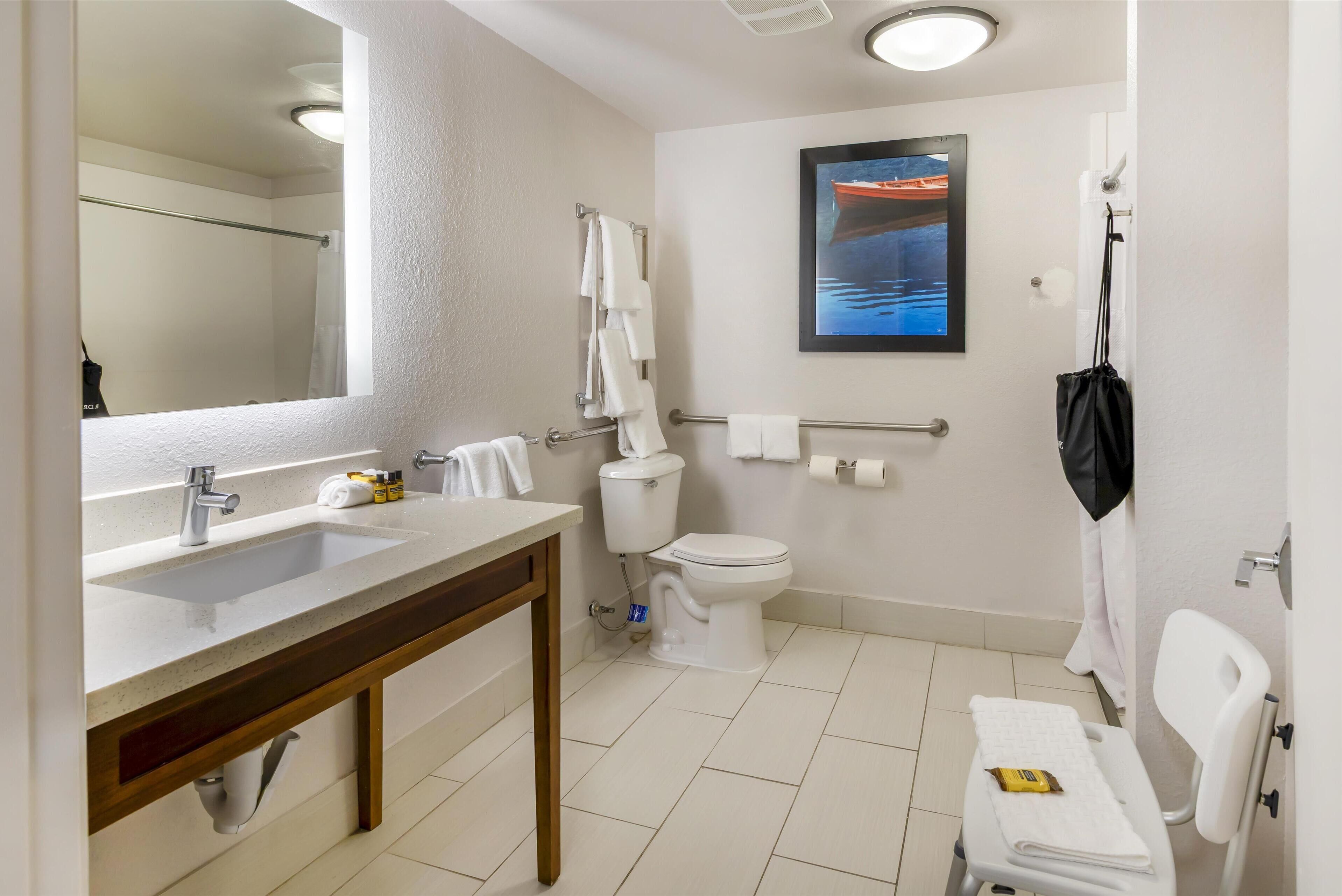 A modern bathroom with a large mirror, a sink, a toilet, and a shower area.