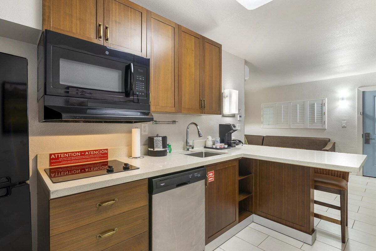 A modern kitchen with wooden cabinets, a microwave, a dishwasher, and a countertop with a sink.