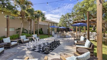 An outdoor patio area with chess tables, outdoor seating, and string lights.