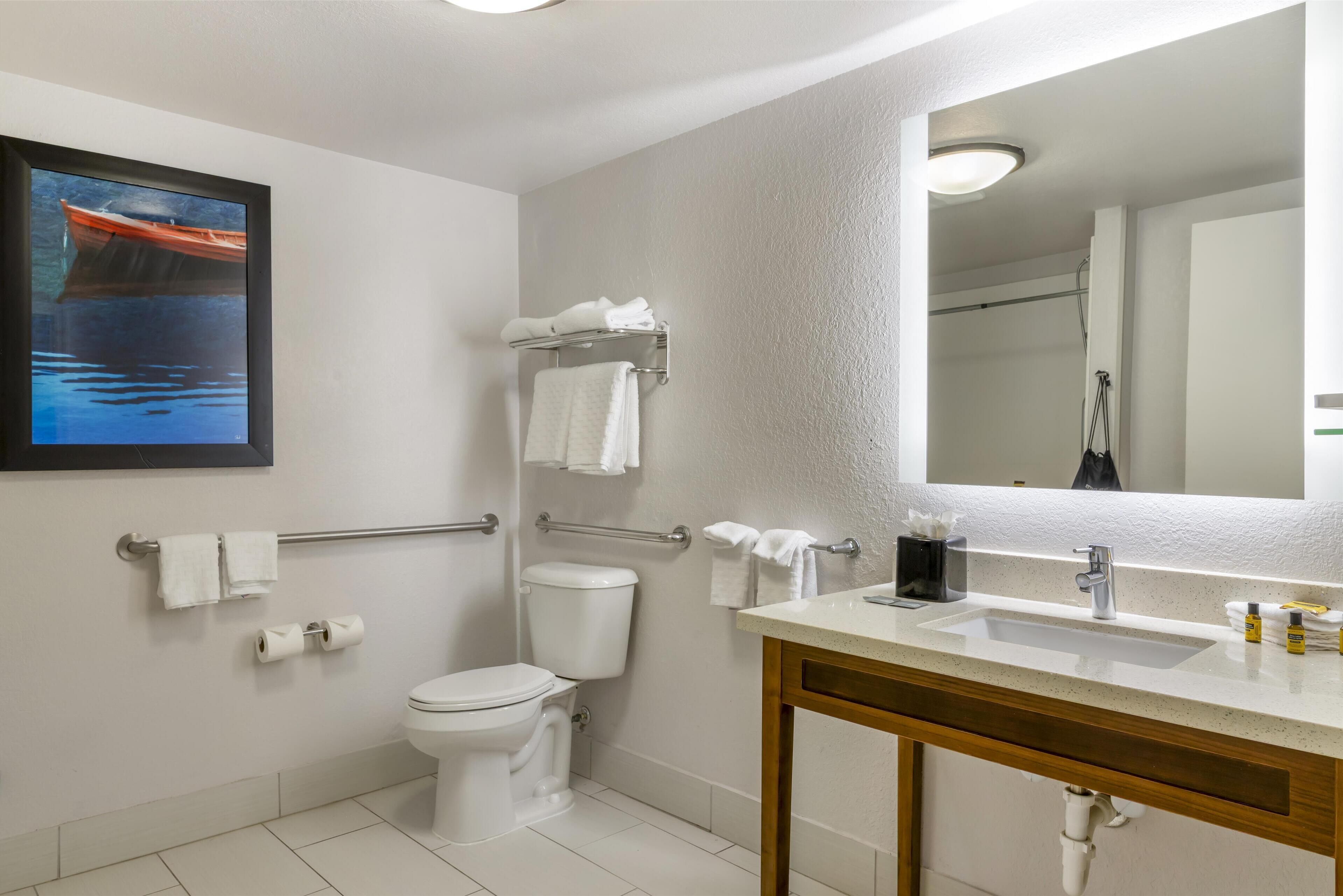 Ein Badezimmer mit Toilette, Waschbecken, Spiegel und Handtuchhalter.
