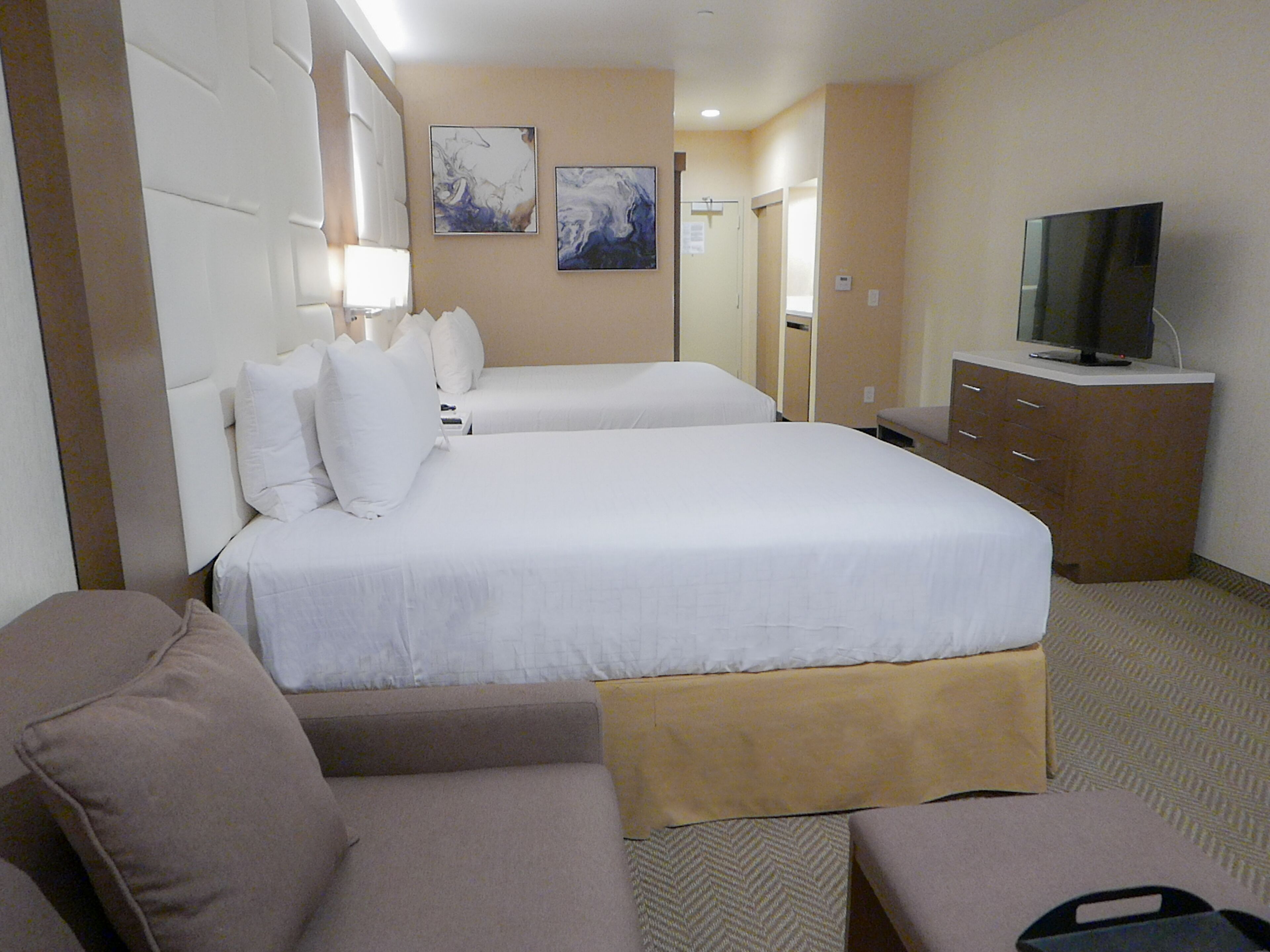 A hotel room with two beds, a television, a desk, and a couch.