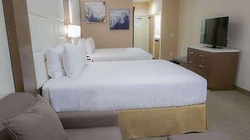 A hotel room with two beds, a television, a desk, and a couch.