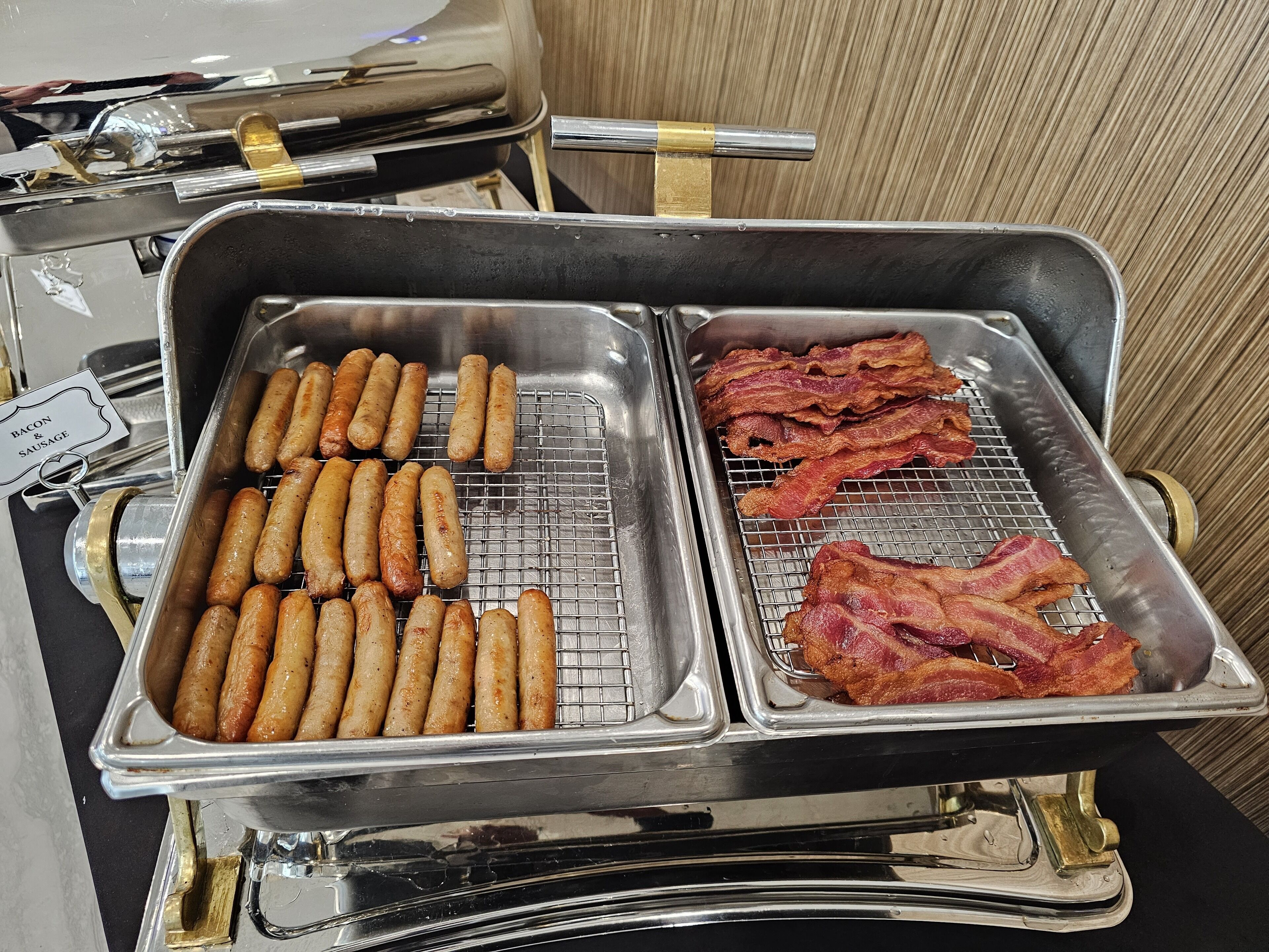 Un buffet avec des plateaux de bacon et de saucisses.