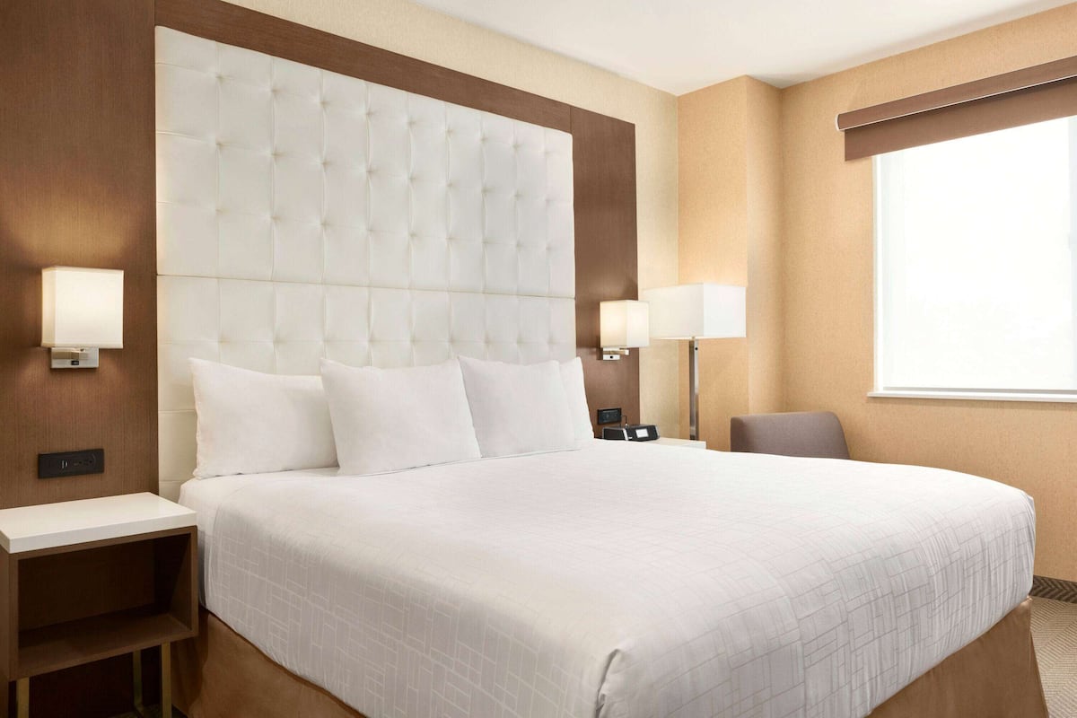 A hotel room with a large bed, two bedside tables, and a window.
