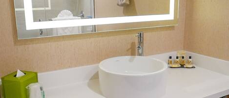 A bathroom with a white sink, a mirror, and a towel rack.