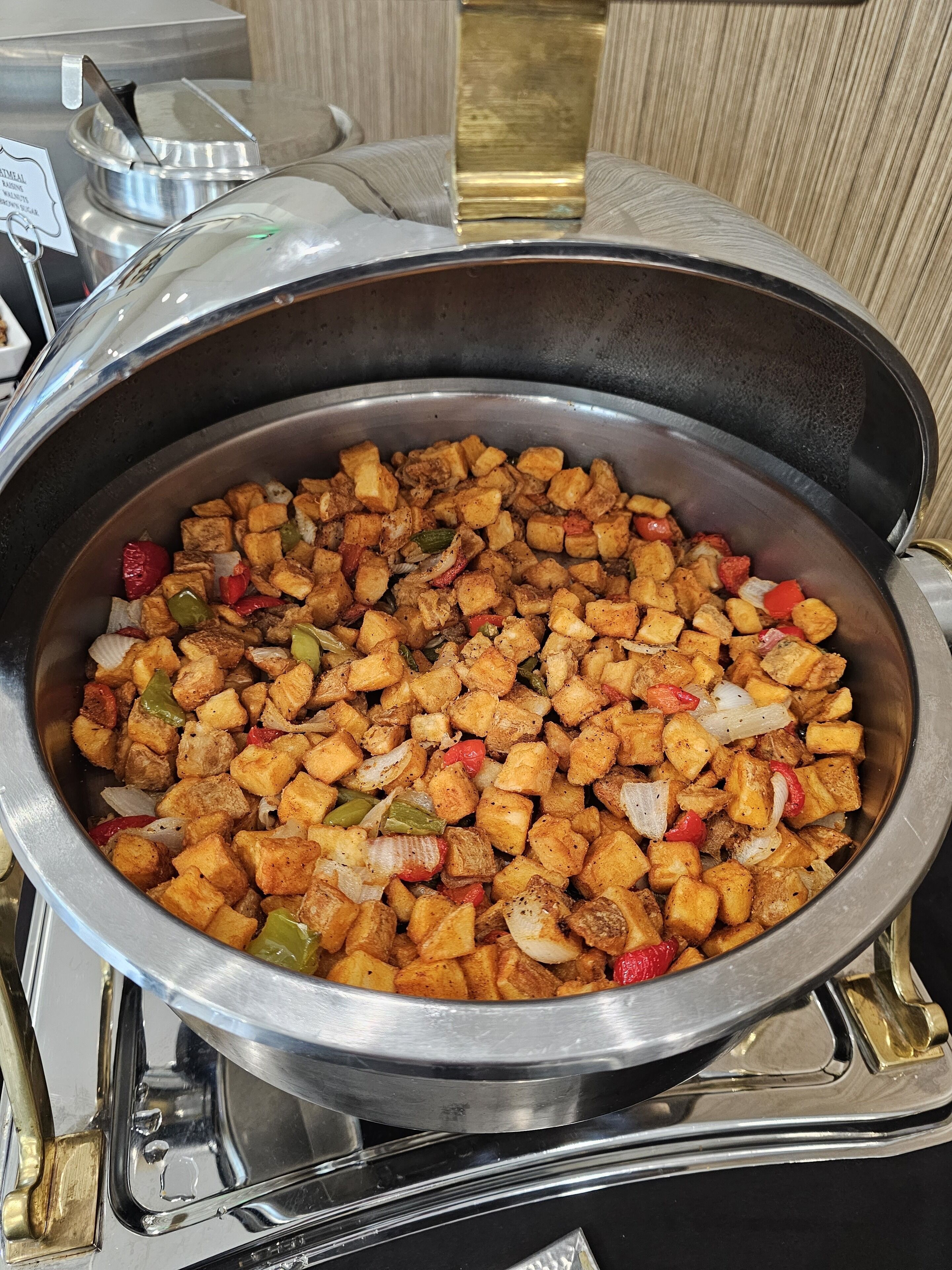 Una sartén de acero inoxidable grande llena de tofu en cubos y verduras, colocada sobre un fogón.
