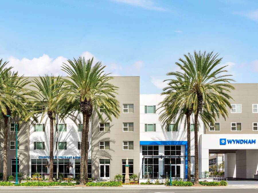 A modern hotel with a flat facade, multiple windows, and a prominent entrance with a blue awning.