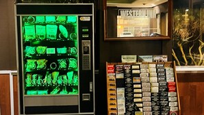 A vending machine with green-lit items and a display of books titled 'Western Wear' and 'Family Adventures.'